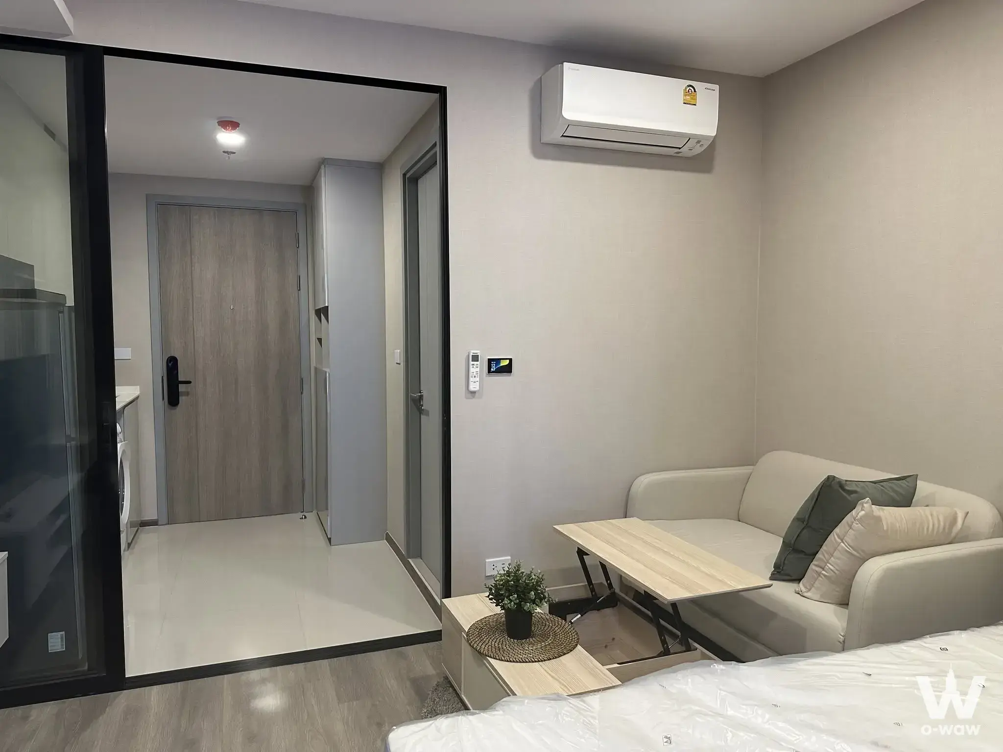 Modern 1-bed condo for rent in SOHO Bangkok Ratchada with open-plan living area, sofa, and kitchenette