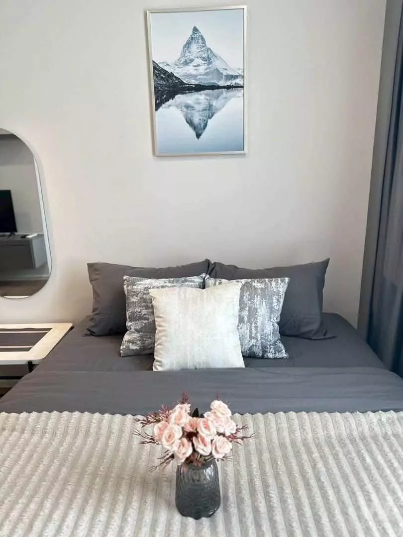 Modern bedroom in 1-bed condo for rent at Modis Rhythm Ramkhamhaeng with grey linens and mountain art