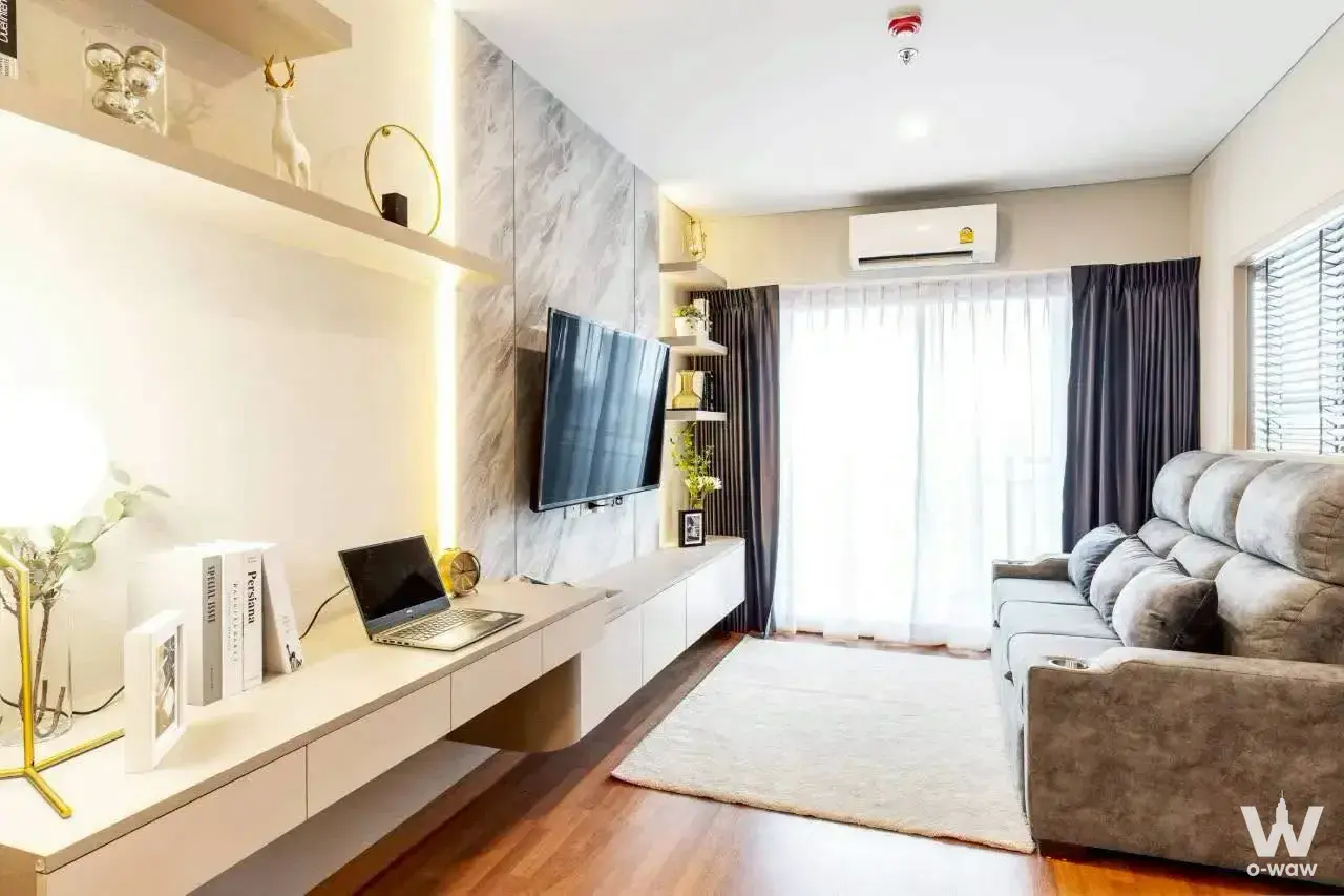 Living room with grey sofa, TV console, and gold accents in a fully furnished Lumpini Place Taopoon Interchange 1-bed condo