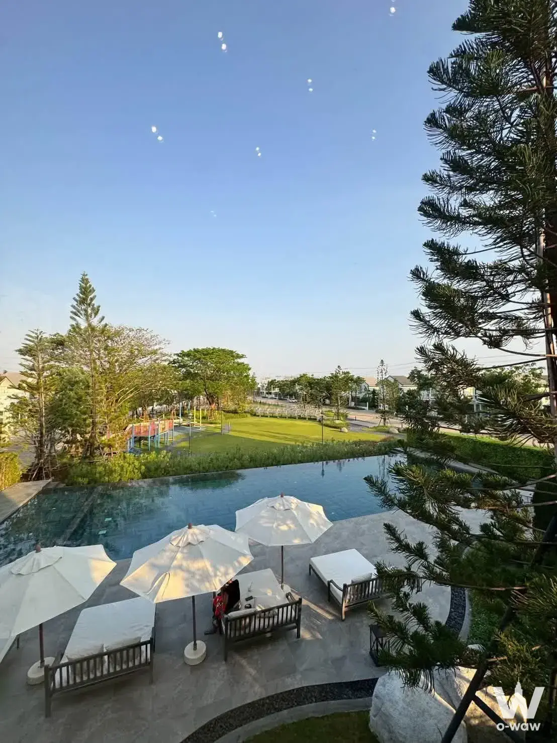 Resort-style pool at 4-bed house for sale in Villaggio 2 Srinakarin-Bangna with lounge chairs and lush greenery