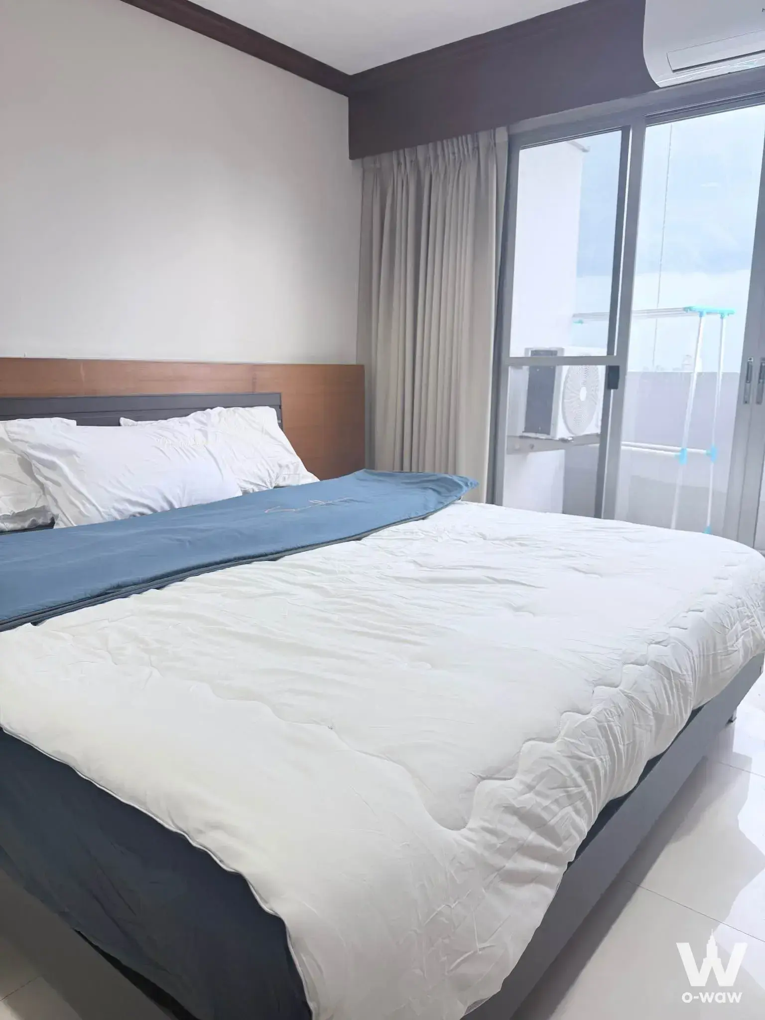 Grey queen bed with blue runner and balcony access in a 2-bed condo for rent at Witthayu Complex
