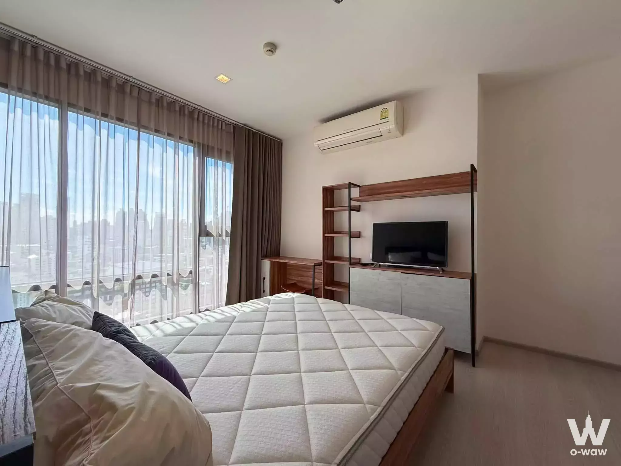 Modern bedroom in 2-bed Rhythm Sukhumvit condo with city views, wooden bed, and minimalist decor