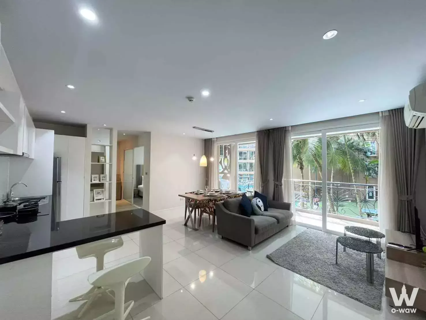 Modern open-plan living area with kitchen peninsula and balcony access in 2-bed condo for rent at Atlantis Condo Resort