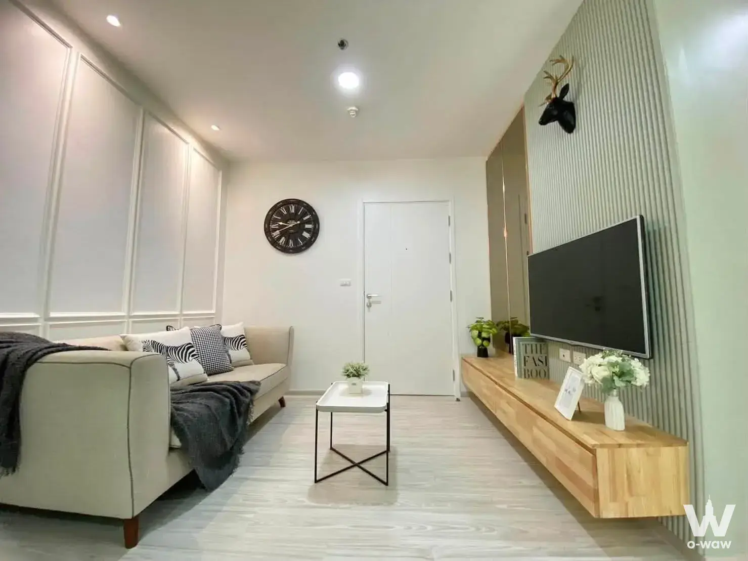 Beige sofa and oak media console in the living room of a furnished 1-bed condo for rent at Aspire Rattanatibet 1
