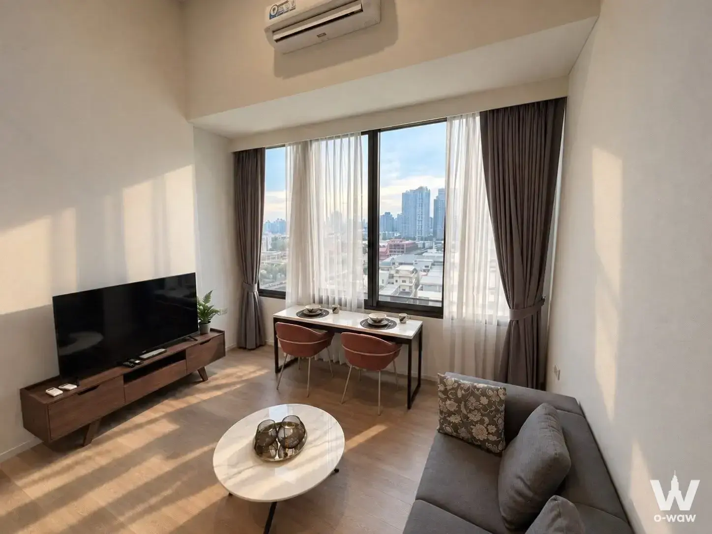 Modern living room for sale in RAMADA RESIDENCE SUKHUMVIT 87 with city skyline view through large sliding windows
