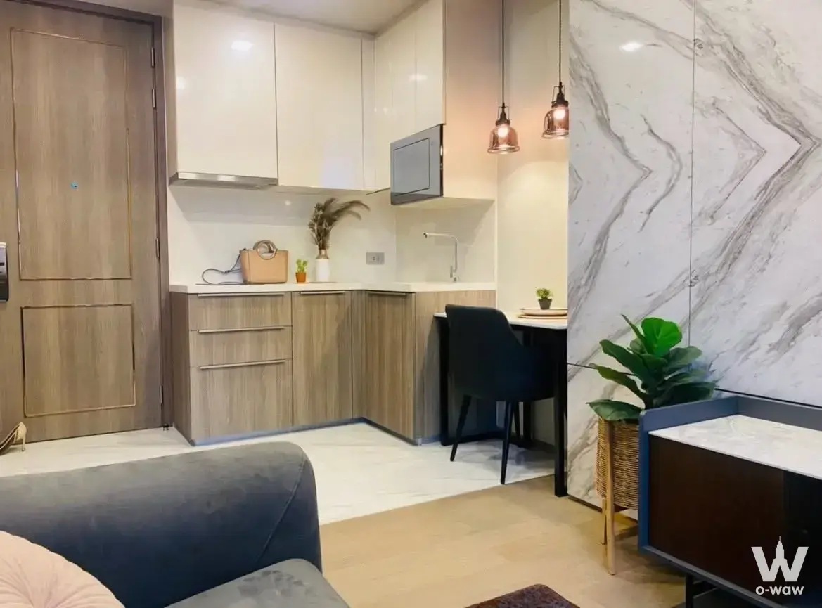 Open-plan kitchen and dining in Celes Asoke 1-bed condo with copper pendants and marble feature wall