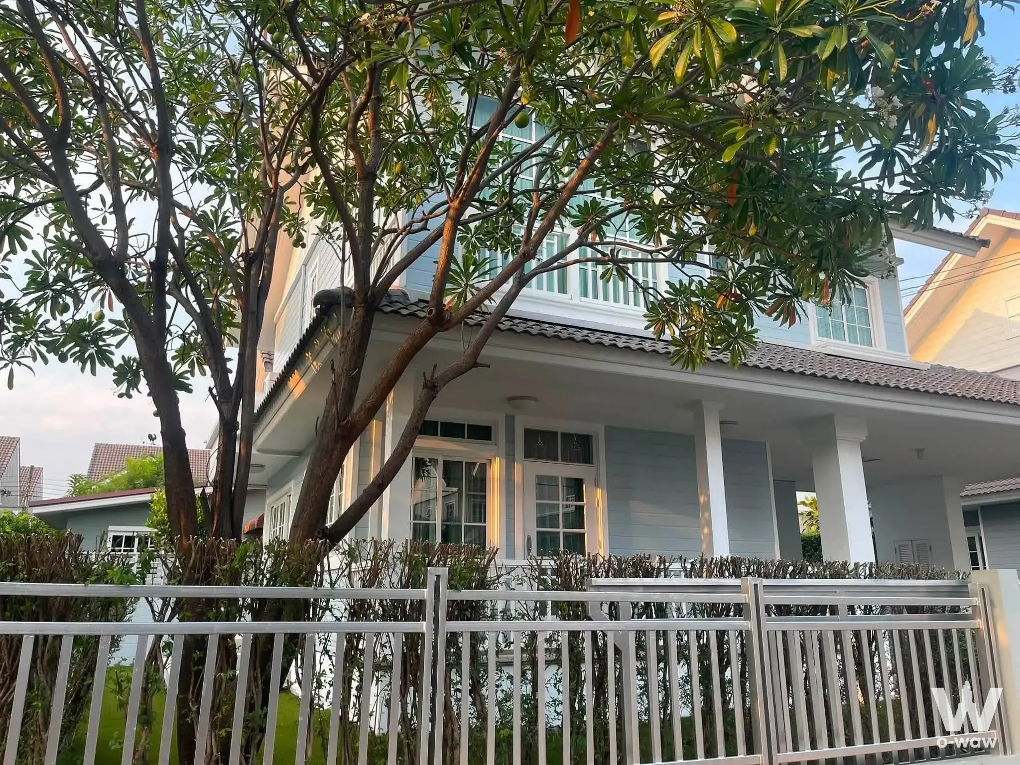 White two-story home with French doors and frangipani tree for rent in Burasiri Panya-Indra