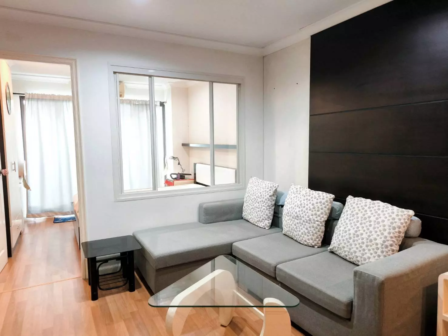 Modern living room with grey sectional sofa and glass coffee table in 1-bed house for rent at Home Lumpini Place Narathiwas
