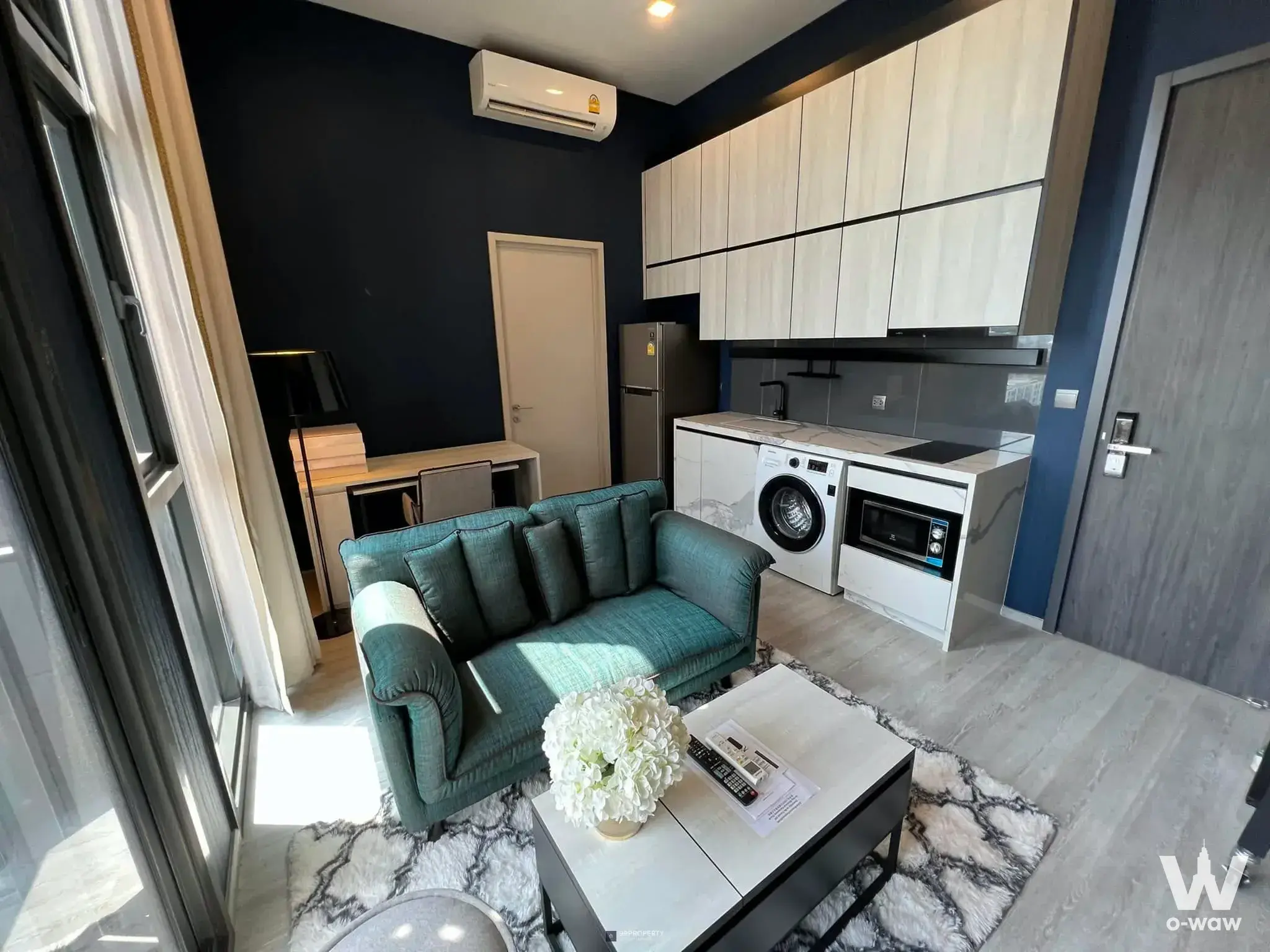 Furnished living area at THE LINE Sukhumvit 71 featuring teal sofa and compact kitchenette