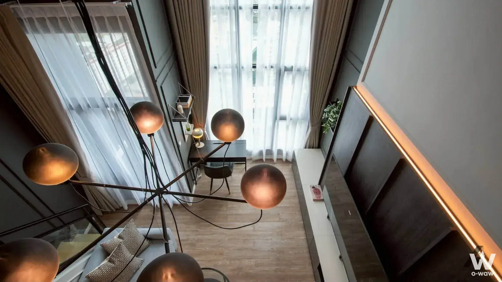 Living room in a Modiz Sukhumvit 50 1-bed condo with a grey sofa, sculptural floor lamp, and wall-mounted TV