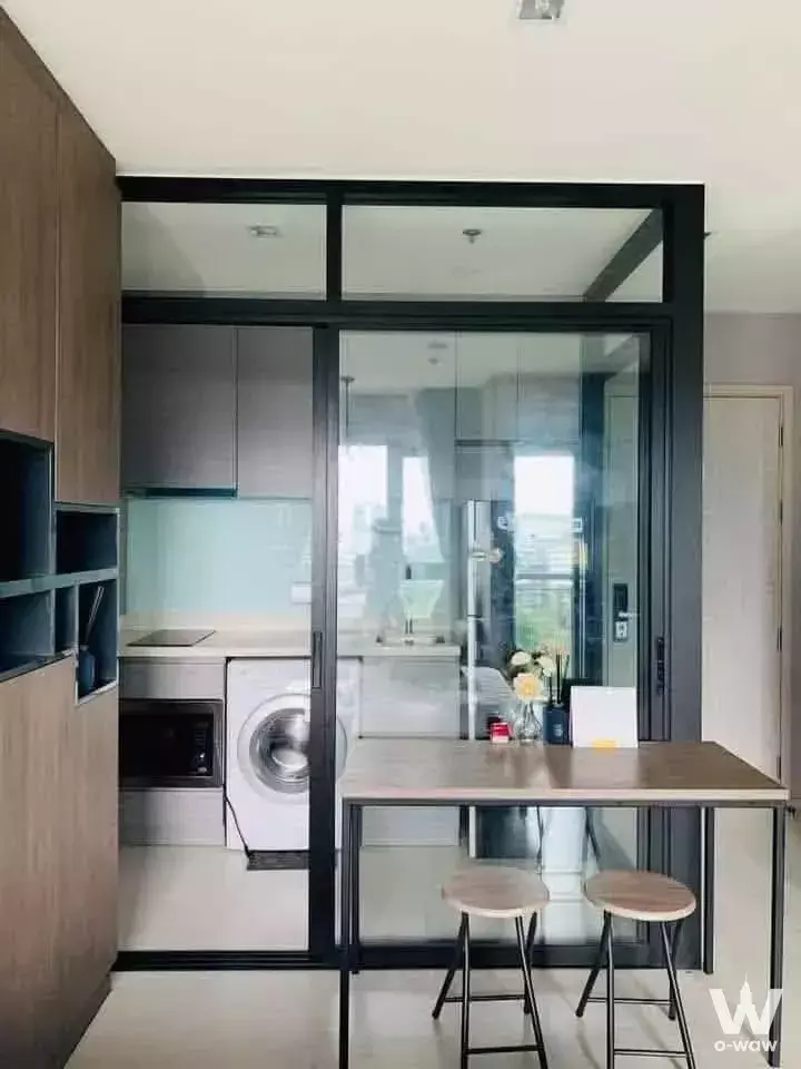 Modern 1-bed condo kitchen in Rhythm Sukhumvit with glass partition, grey cabinets, and dining nook