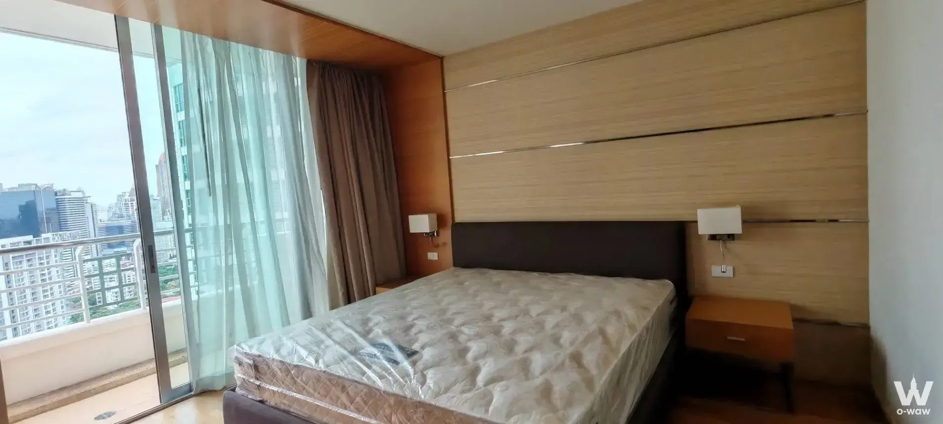 Sathorn Prime Residence 1-bed condo master bedroom with wood panel wall and city skyline view