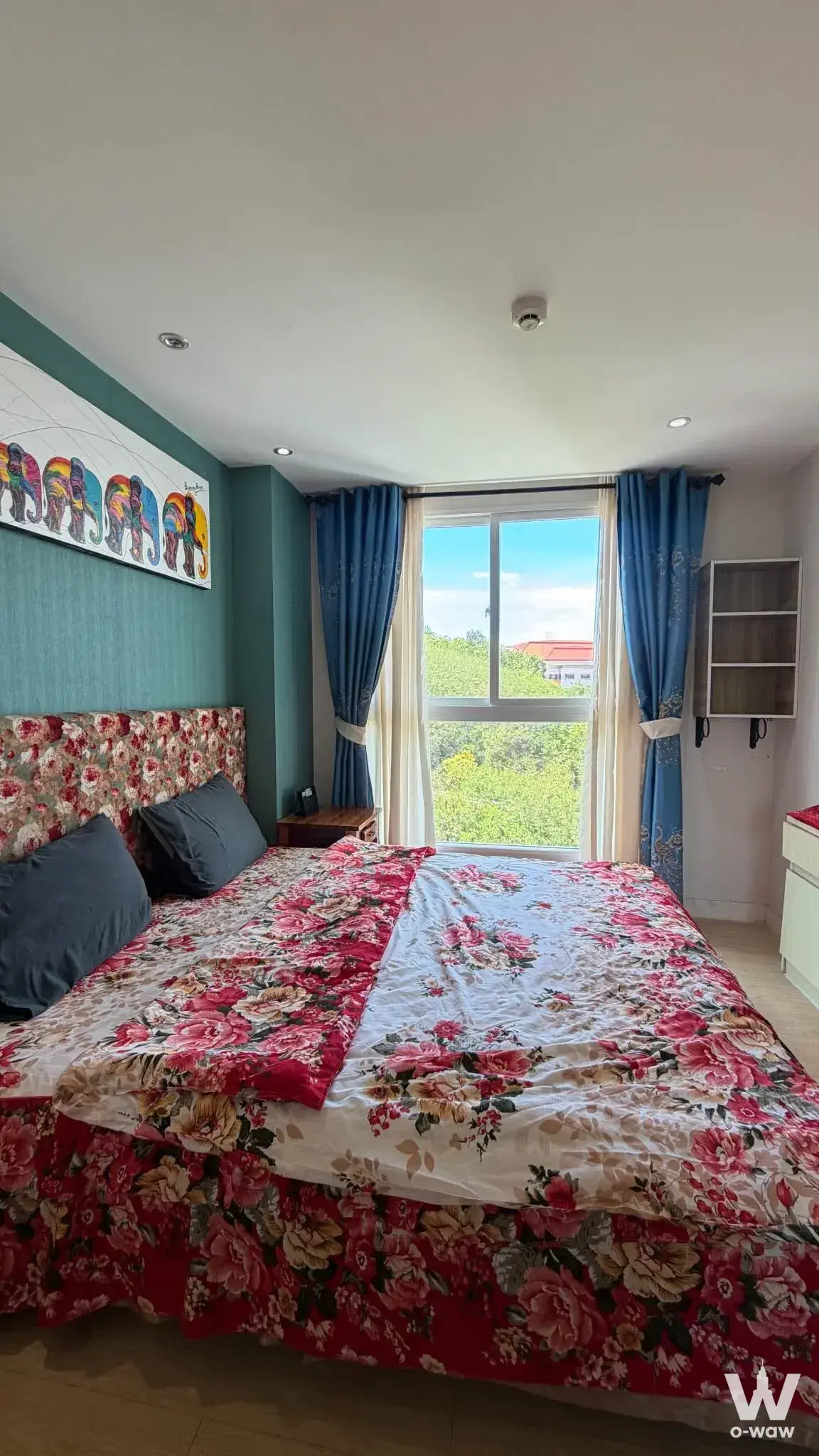 1-bed condo for rent in Grande Caribbean Condo bedroom with teal accent wall, elephant art, and tree canopy view