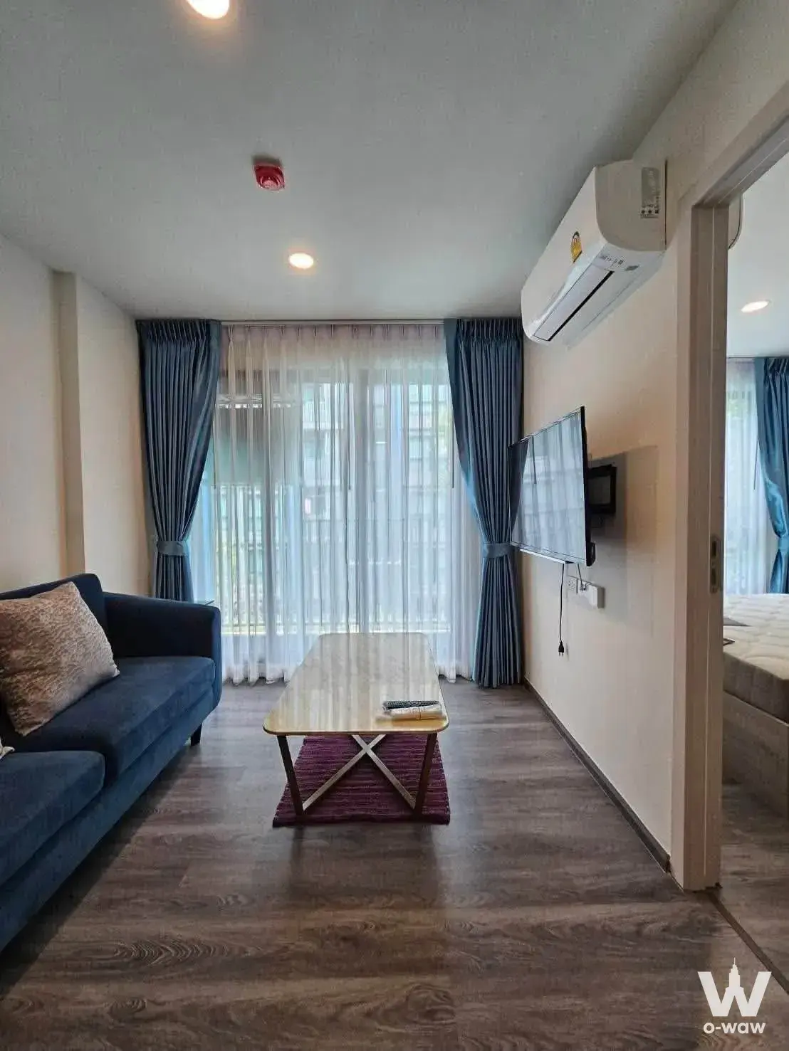 Modern living room in 1-bed condo for sale at The Origin Onnut featuring navy sofa, marble coffee table, and