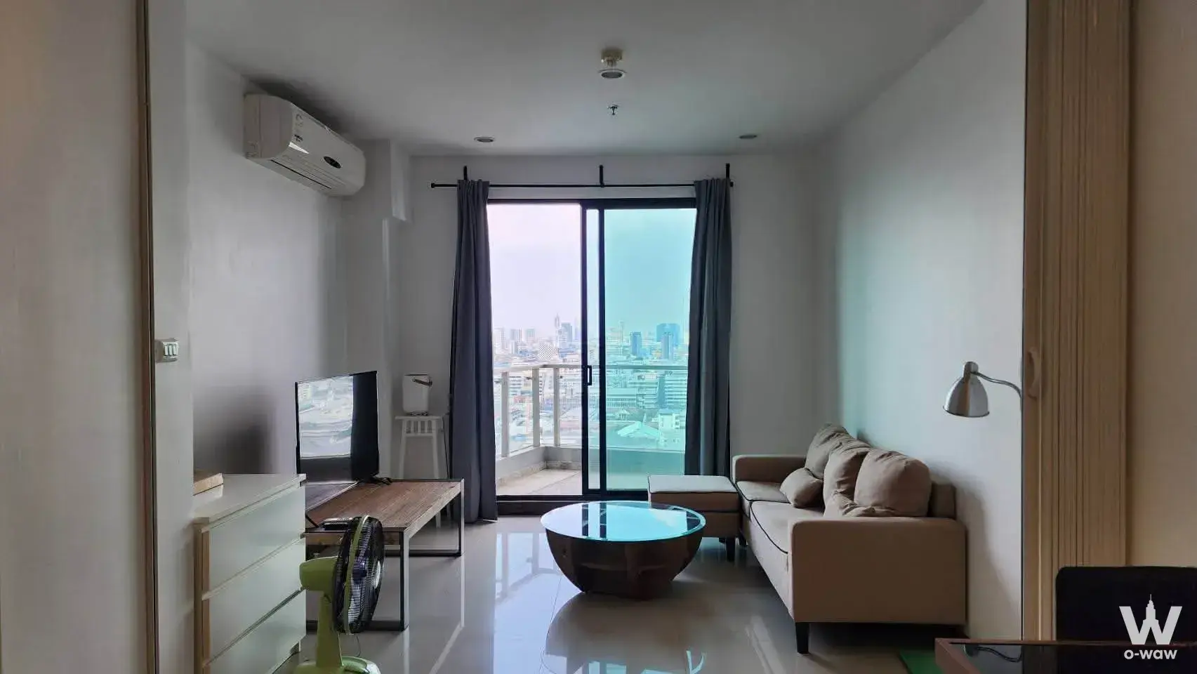 1-bed condo for sale in Supalai Premier Ratchathewi featuring beige sofa, glass coffee table, and balcony view