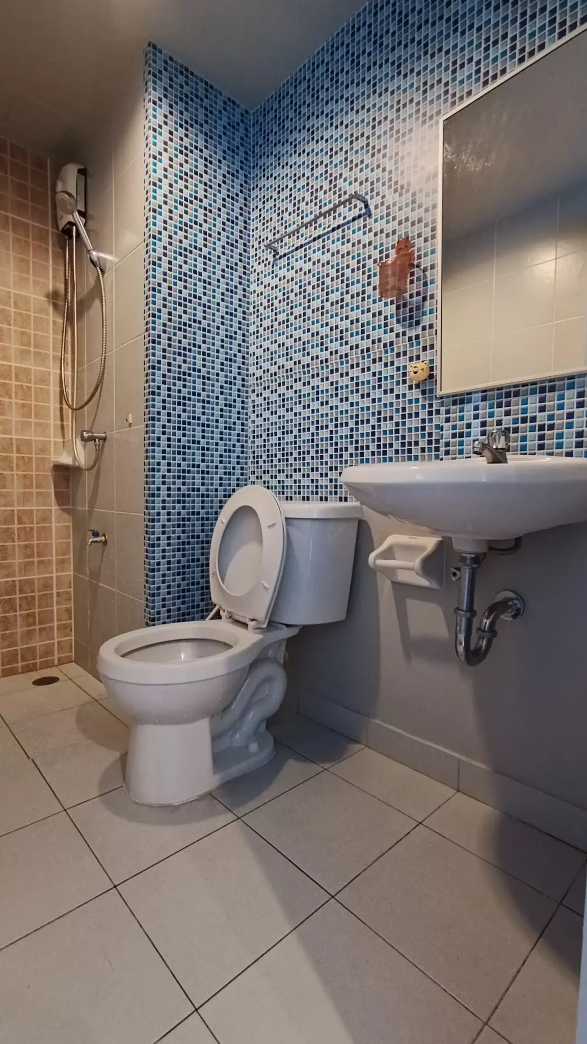Compact bathroom with blue mosaic tiles, pedestal sink, and shower in Lumpini Seaview Cha-am condo for rent