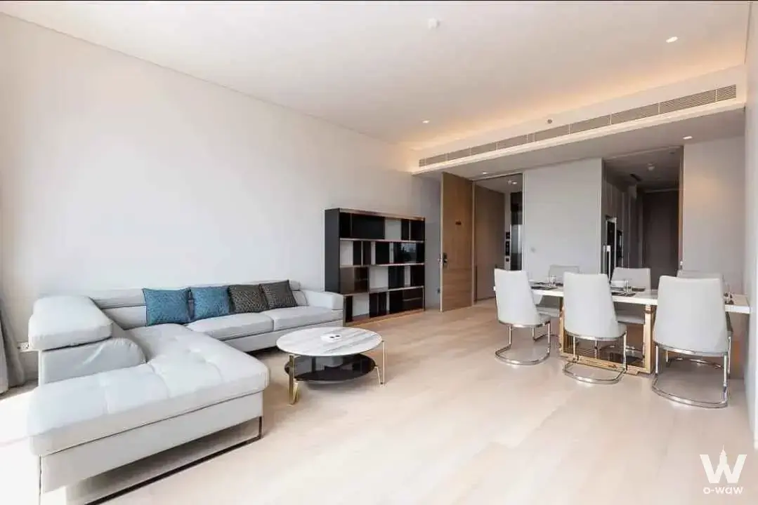 Living room in a Tela Thonglor 2-bed condo featuring grey leather sectional and round marble coffee table
