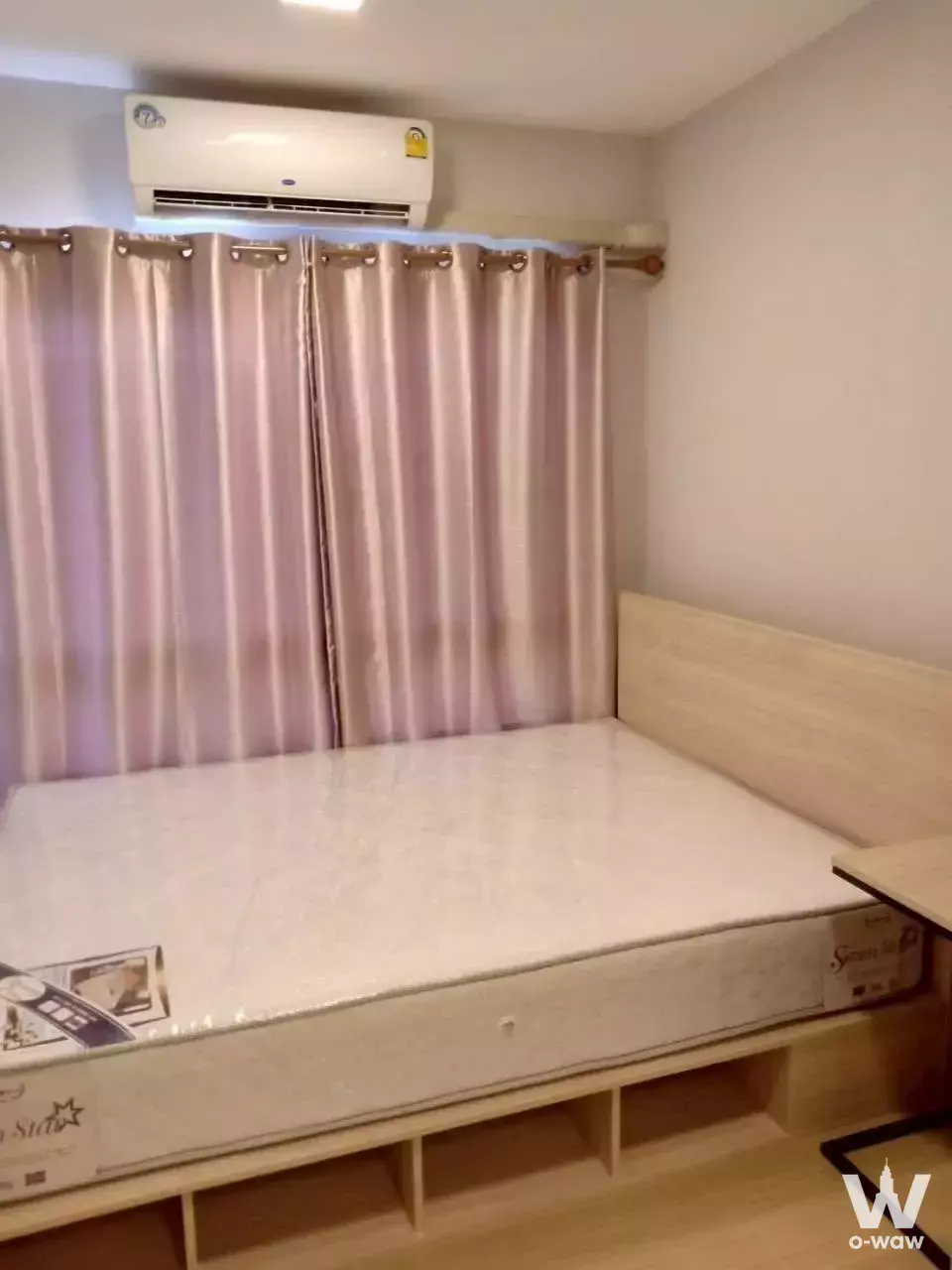 Modern bedroom in 1-bed condo for rent at Plum Condo Rangsit Alive 1 with light wood bed frame and mauve curtains
