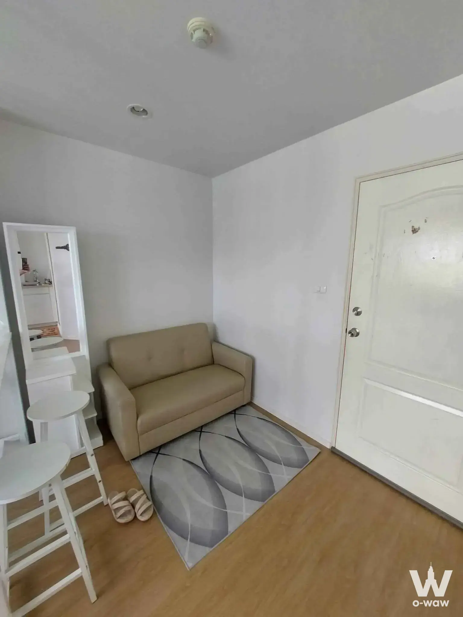 Compact 1-bed condo living room in Lumpini Condo Town Nida SeriThai with beige sofa and geometric rug