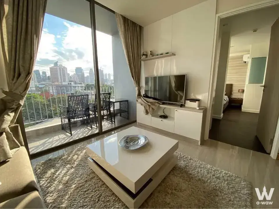 Modern 1-bed condo living room in Downtown49 with city skyline view, beige sofa, and balcony seating