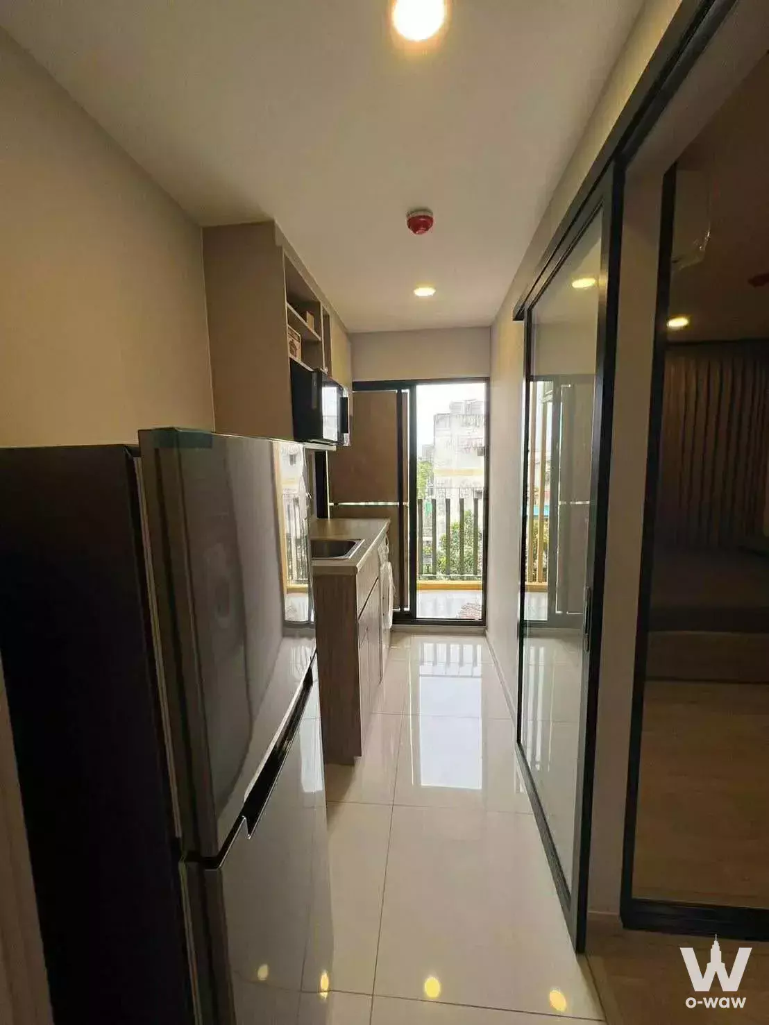 Modern kitchen corridor in 1-bed condo for rent at Plum Condo Sukhumvit 97.1 with stainless steel fridge and glass partition