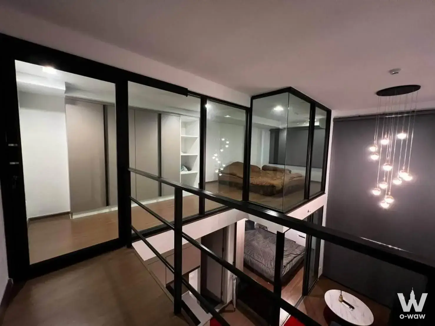 Duplex loft interior in an Ideo New Rama 9 condo featuring glass partitions and light wood flooring