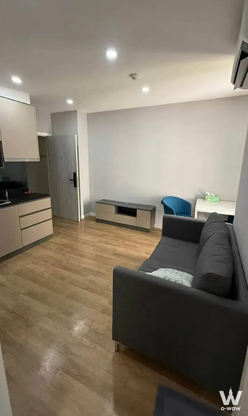 Groove Ratchada-Rama 9 2-bed condo open-plan studio with light wood flooring, grey sofa, and modern minimalist kitchen