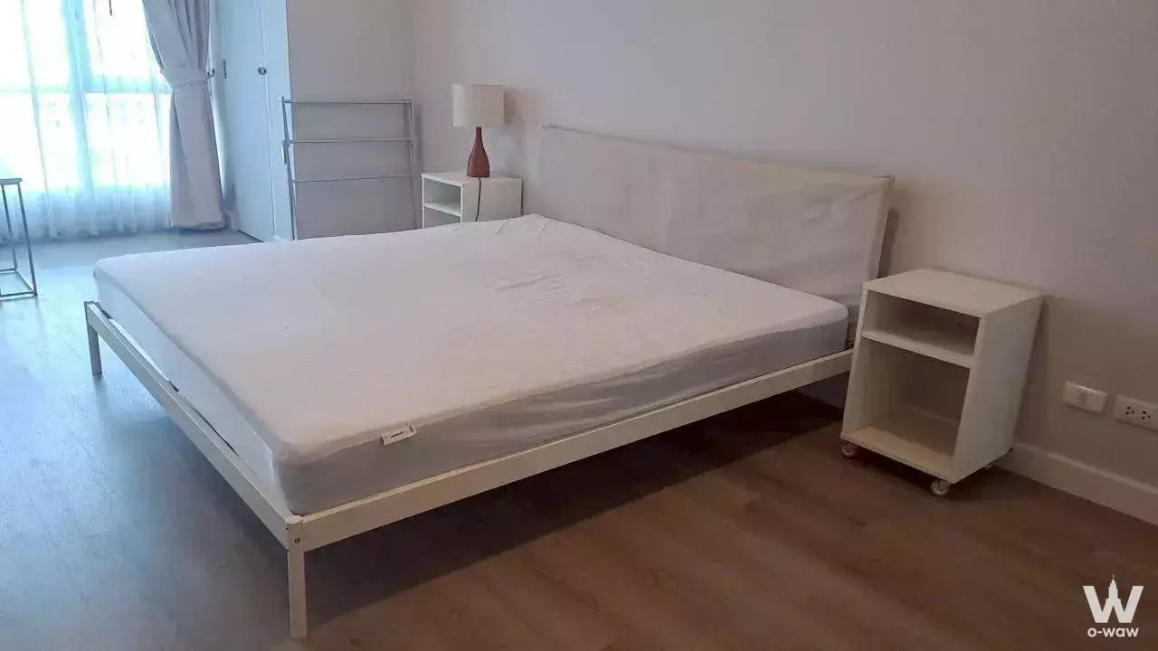 Minimalist bedroom in 1-bed condo for rent at The Trendy Condominium featuring light wood floors and natural light