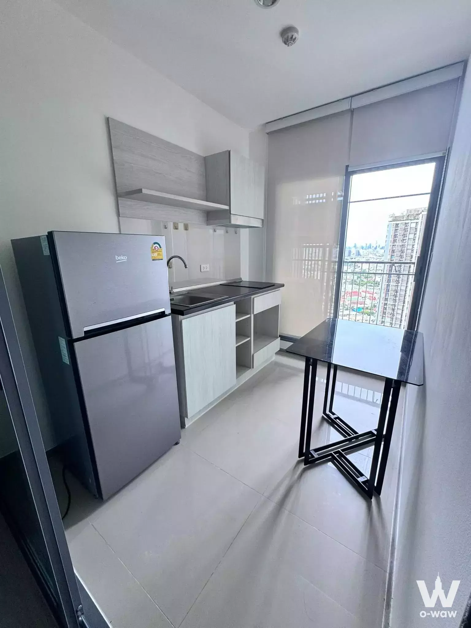Modern kitchenette in 1-bed condo for sale at ASPIRE SATHORN-RATCHAPRUK with wood cabinets and city view