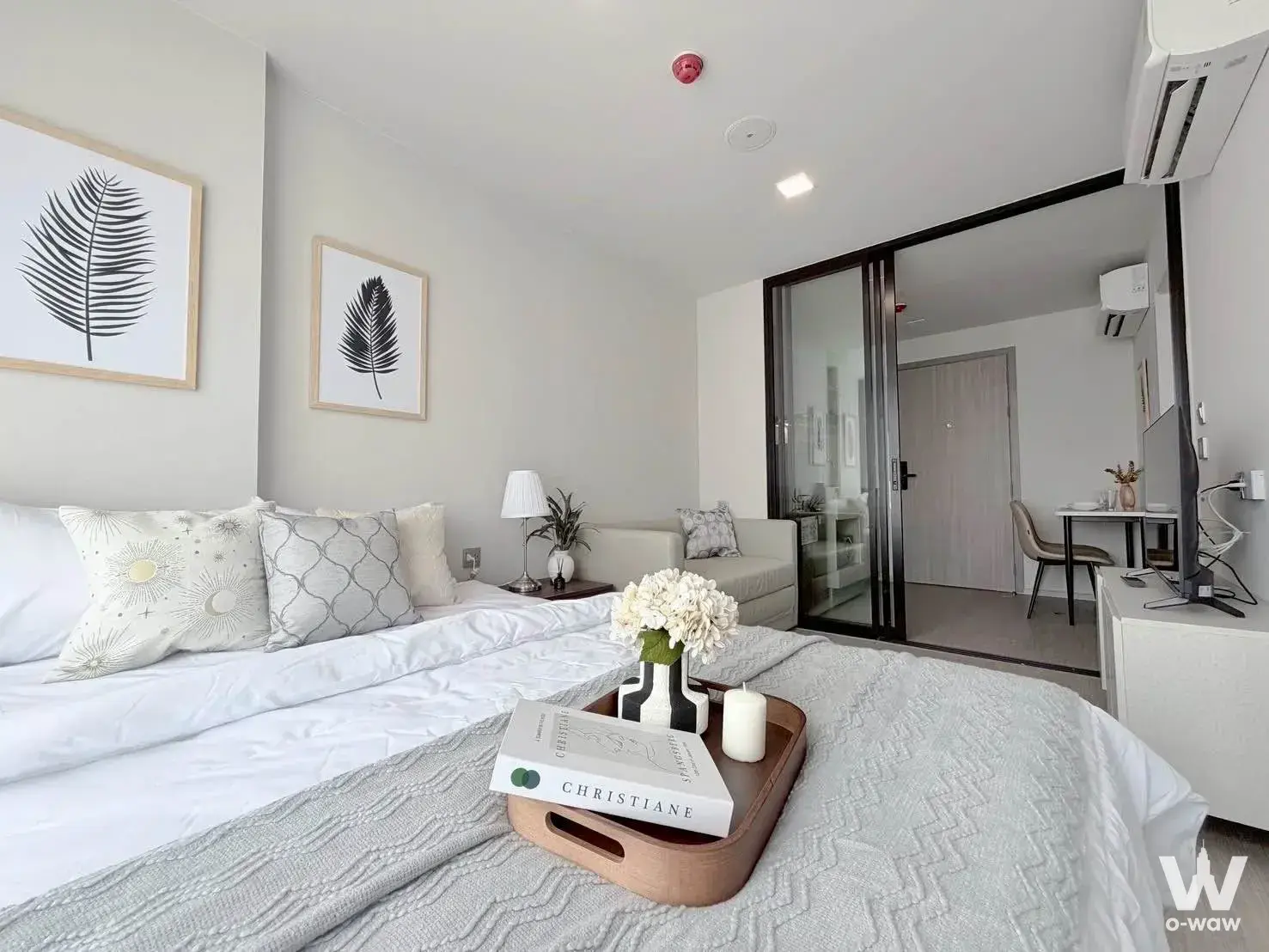 Modern bedroom in 1-bed condo for rent at Atmoz Oasis Onnut with queen bed, botanical prints, and glass door to living area