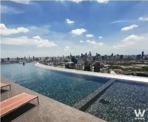 Rooftop infinity pool with sun loungers overlooking the Bangkok skyline at The Lumpini 24