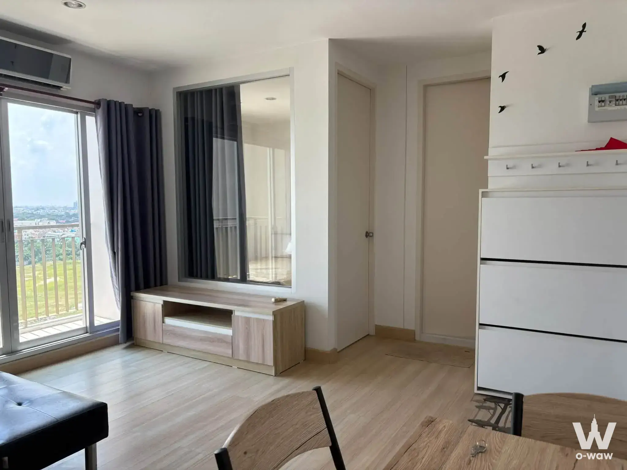 Modern living room with balcony access and city views in The Parkland Srinakarin condo for sale