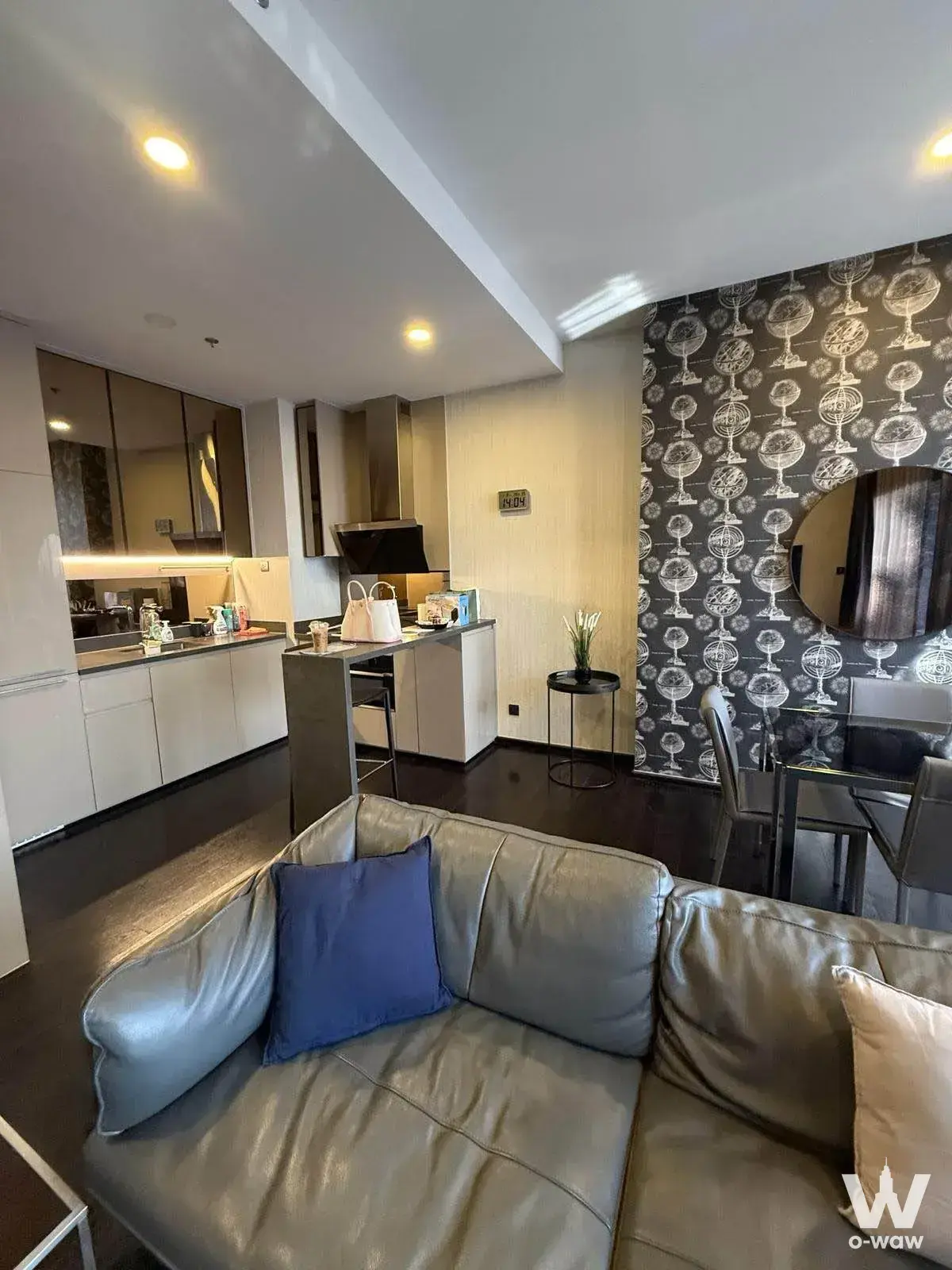Open-plan living and dining area in a Park Thonglor Tower condo with taupe sectional sofa and patterned feature wall