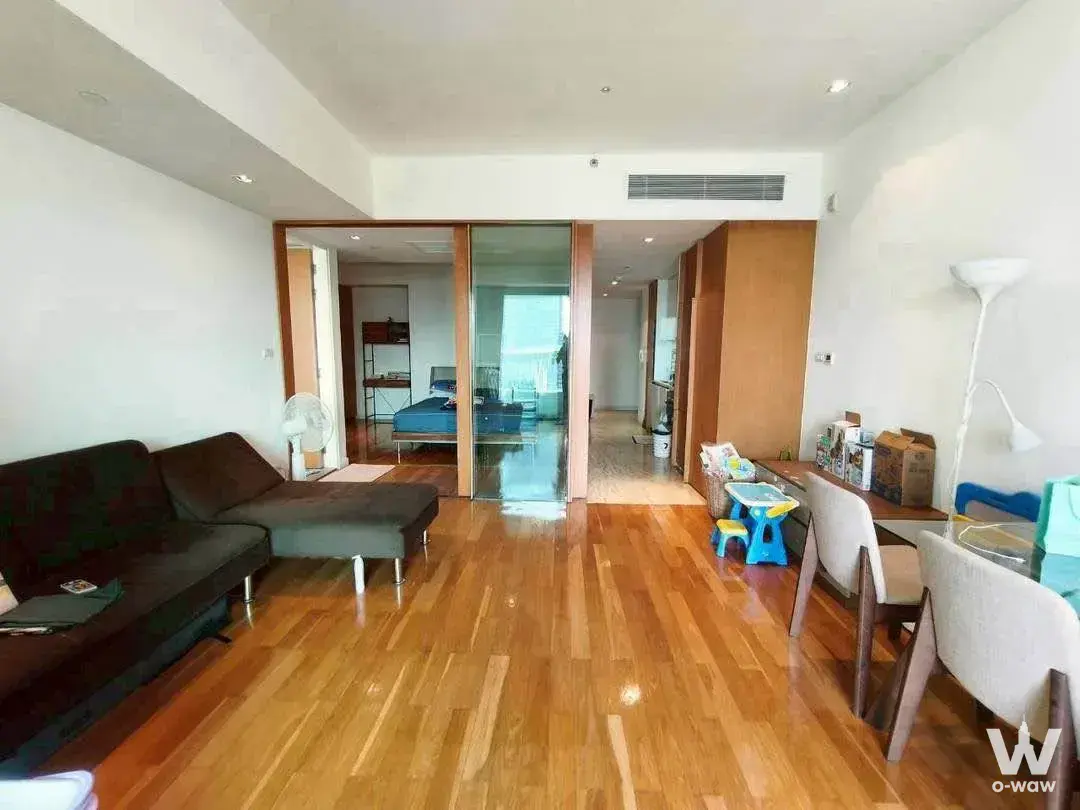 Open-plan living dining space with dark L-shaped sectional sofa and glass-top dining table