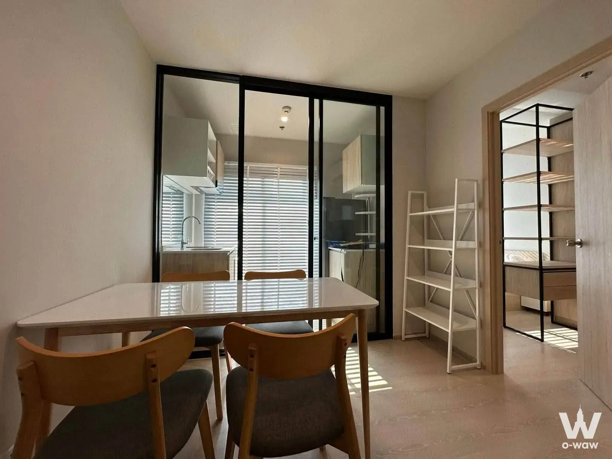 Modern dining area in 1-bed condo for rent at NUE Noble Ngamwongwan with white table and glass partition