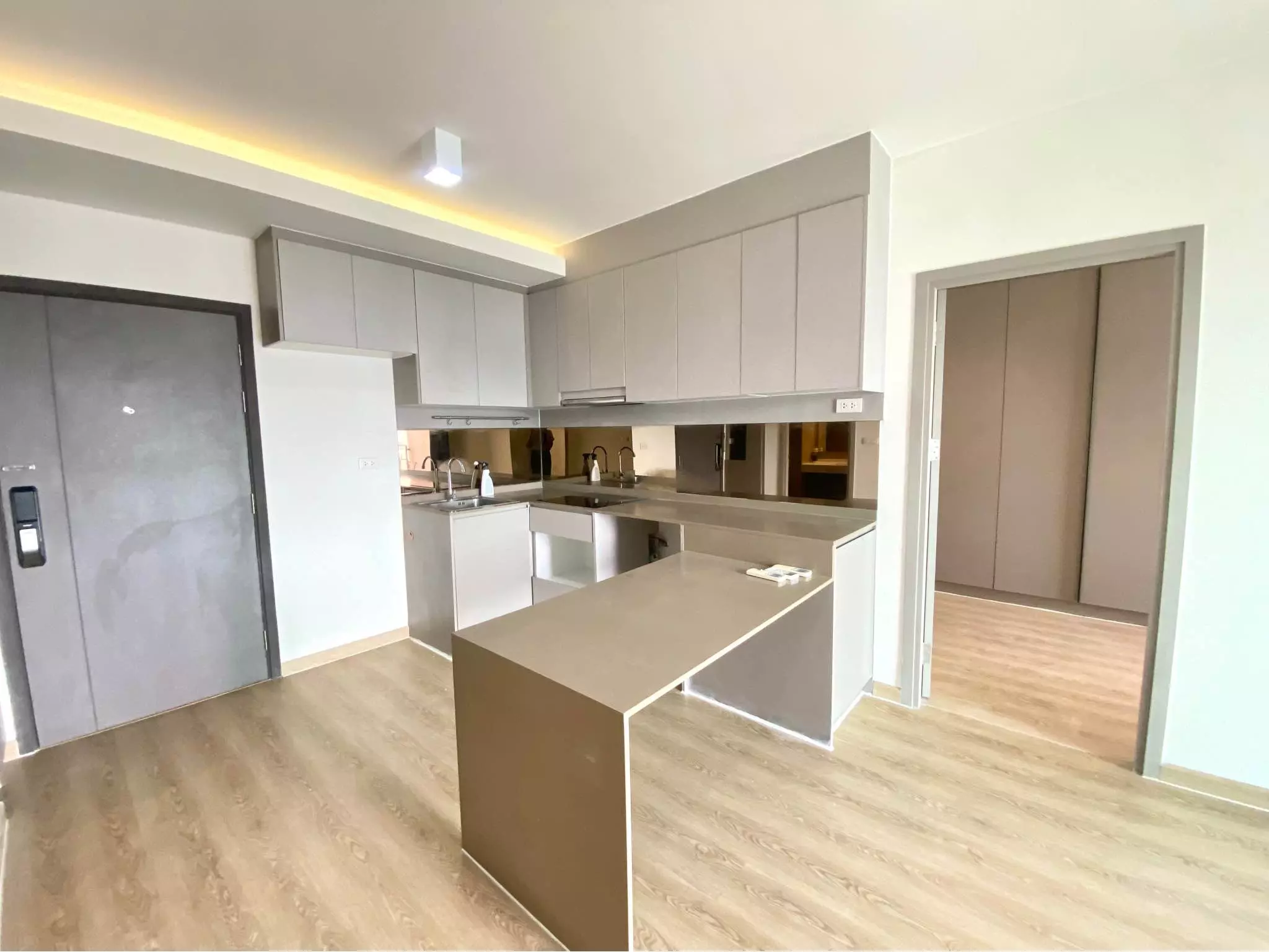 Modern open-plan kitchen with grey cabinets and oak floors in 2-bed condo for sale at Ideo Sukhumvit 93