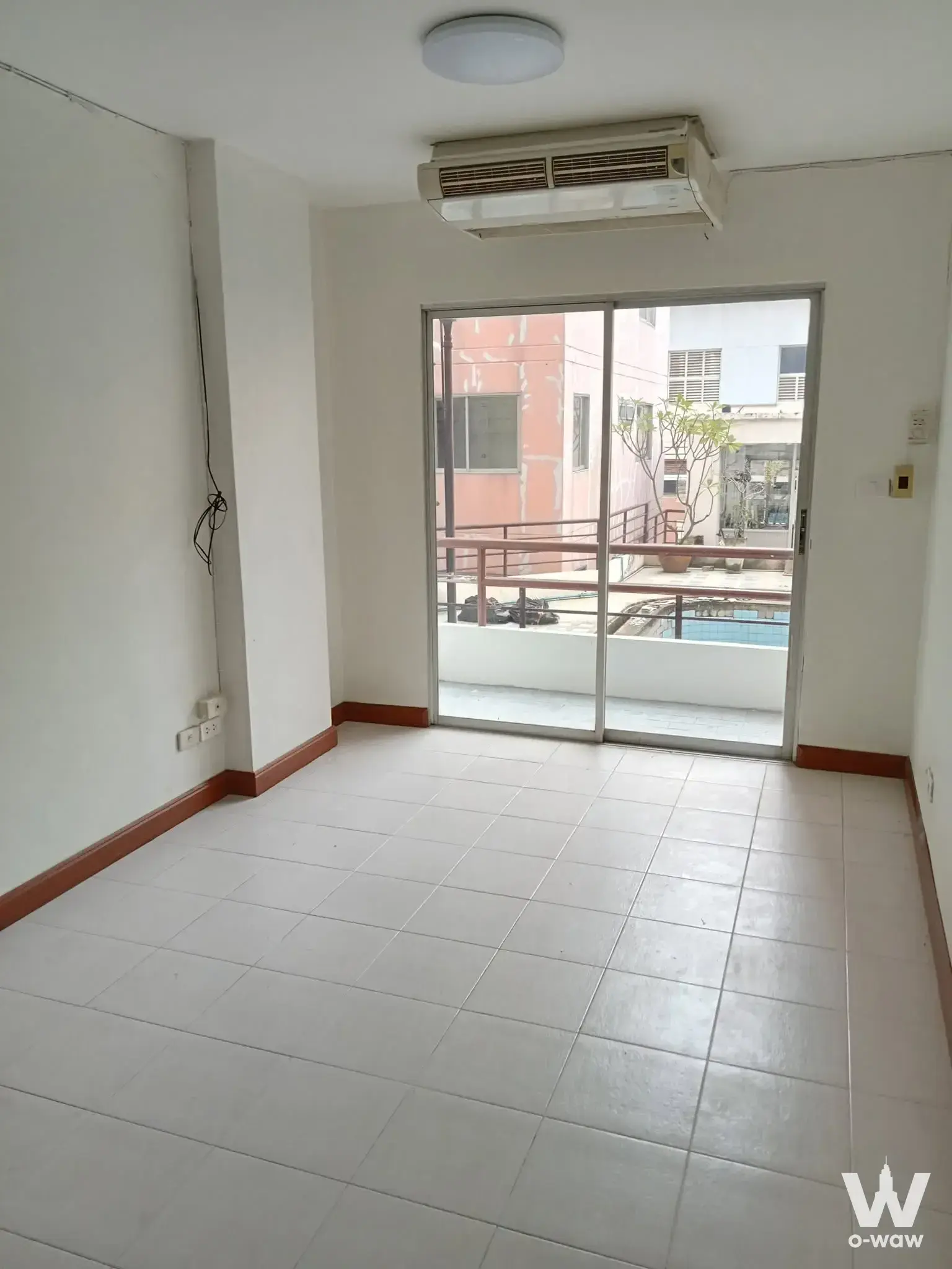 Empty unfurnished living room with glossy white tile floors and sliding glass doors to a balcony