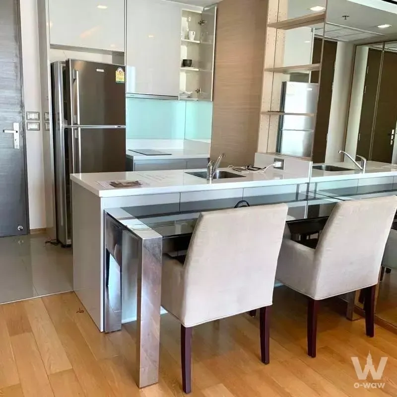 Modern open-plan kitchen with white island and beige dining chairs in 1-bed condo for rent at The Address Asoke