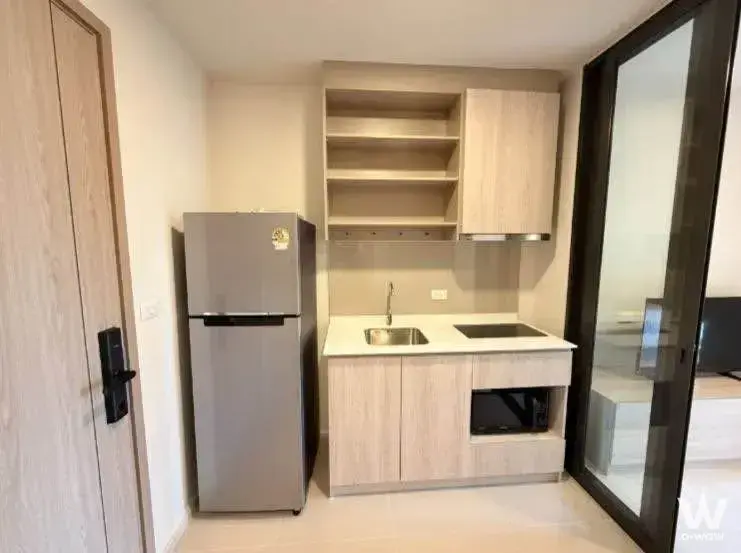 Compact kitchenette in 1-bed FLO by Sansiri rental with light wood cabinets and smart lock