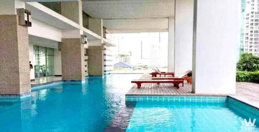 Outdoor pool area with wooden deck and lounge chairs in The Light house Sathorn-Charoennakorn condo for rent