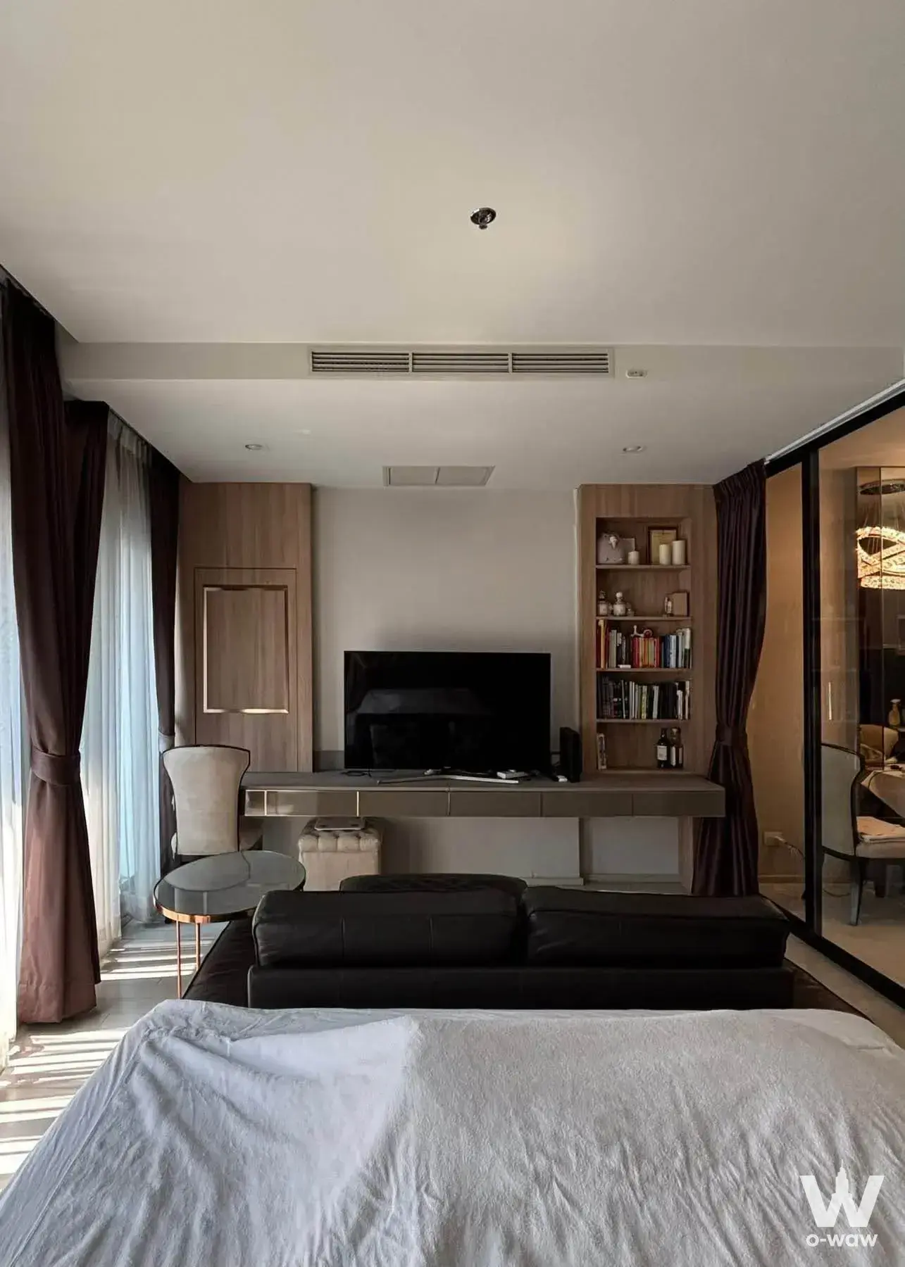 Modern master suite with floating desk and black leather sofa in a 1-bed condo for rent at Noble Ploenchit