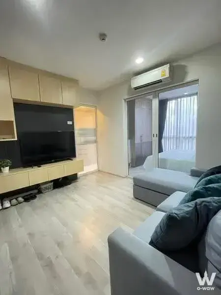Modern living room featuring grey sectional sofa, light wood cabinetry, and balcony access