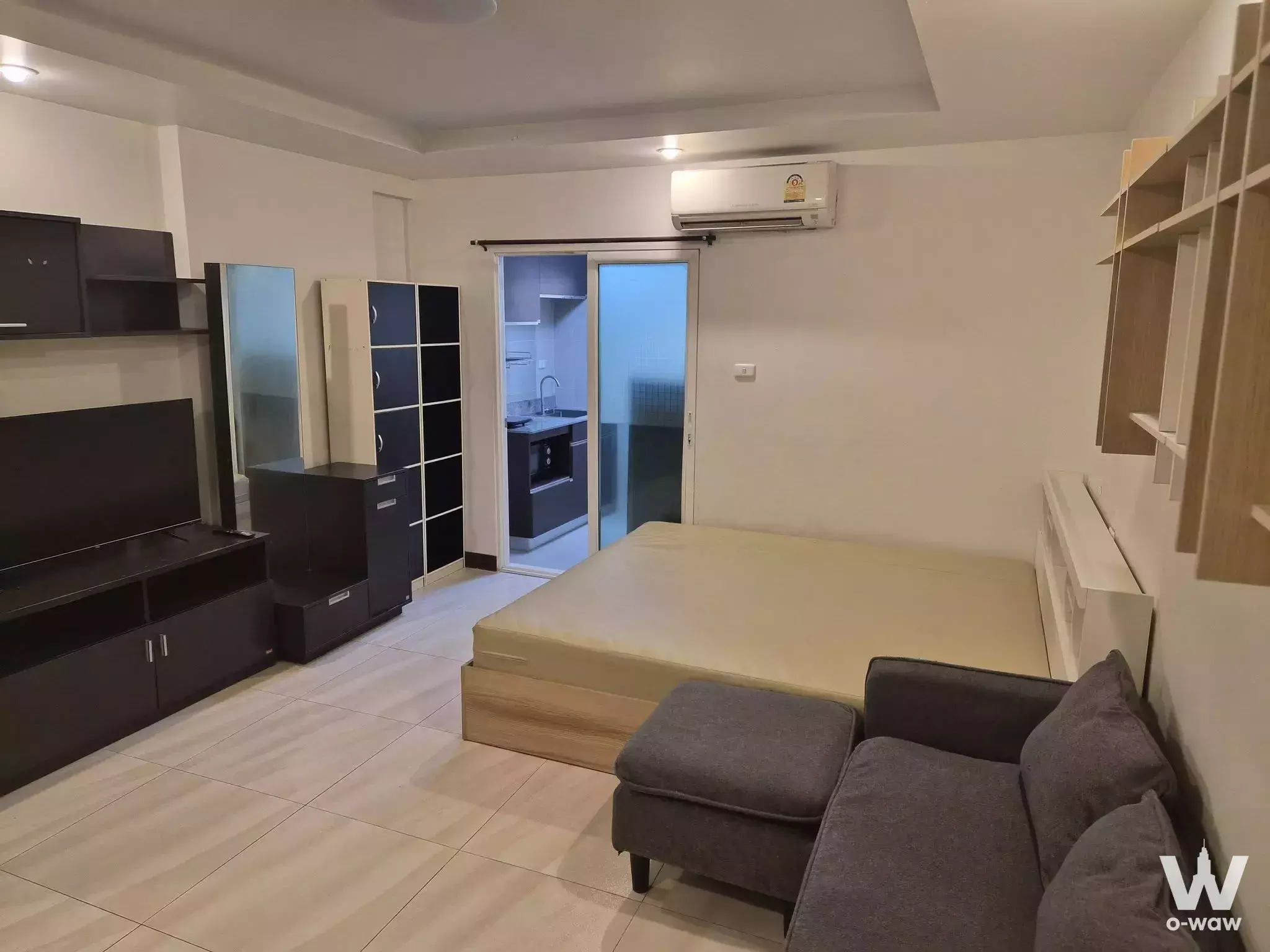 Modern 1-bed condo for sale in Happy Condo Rachada 18 with queen bed, sofa, and open kitchenette view