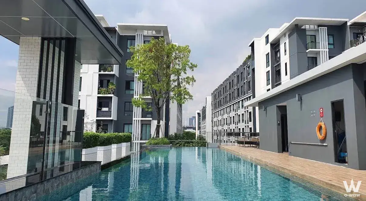 Long rectangular swimming pool surrounded by modern buildings at Notting Hill Sukhumvit 105