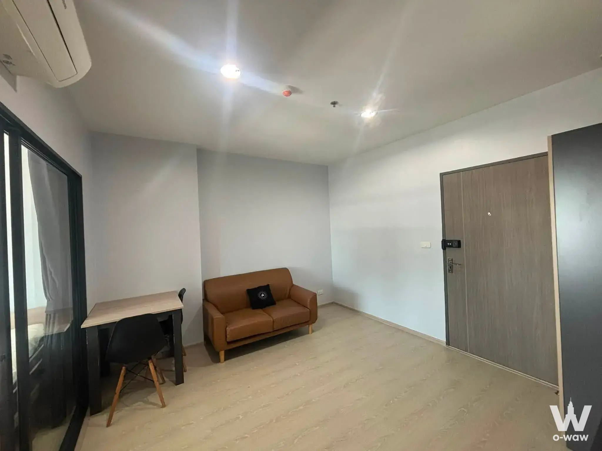 Spacious living area in IDEO Sukhumvit 115 rental featuring leather sofa, dining set, and modern minimalist design