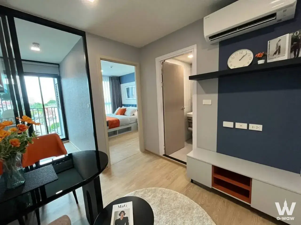 Furnished living room with navy accent wall, orange dining chair, and balcony city view