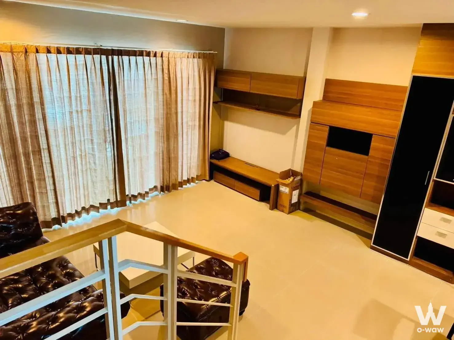 Loft living area with dark leather sofa and high ceilings in Baan Klang Muang townhouse