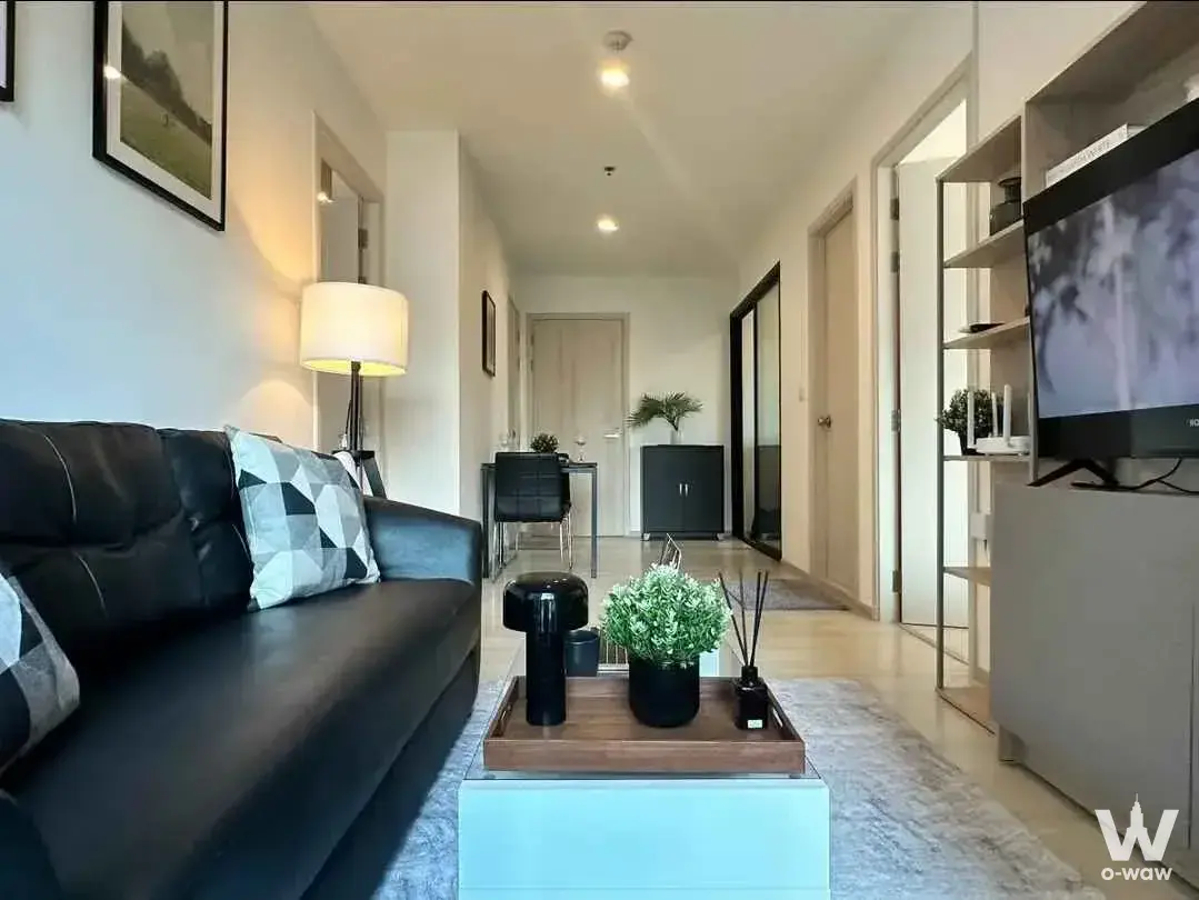 Modern living room in a Life Asoke 2-bed condo with a black leather sofa and light wood coffee table