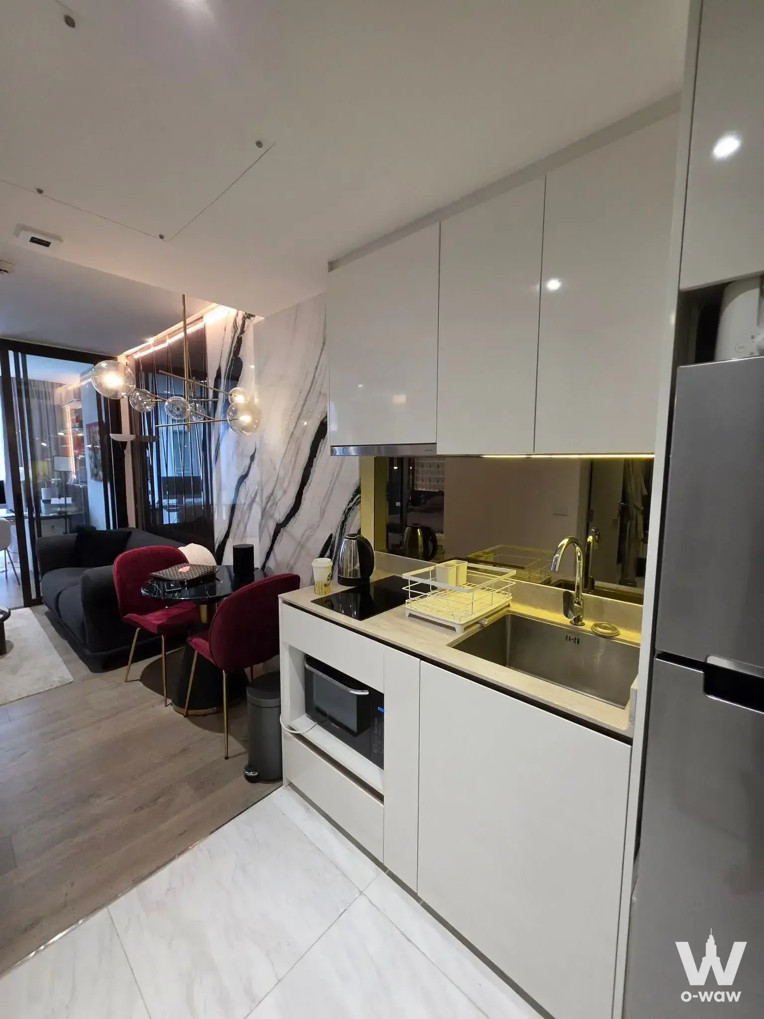 Modern open-plan kitchen and living area in 1-bed condo for rent in Fynn Asoke featuring white marble walls and burgundy