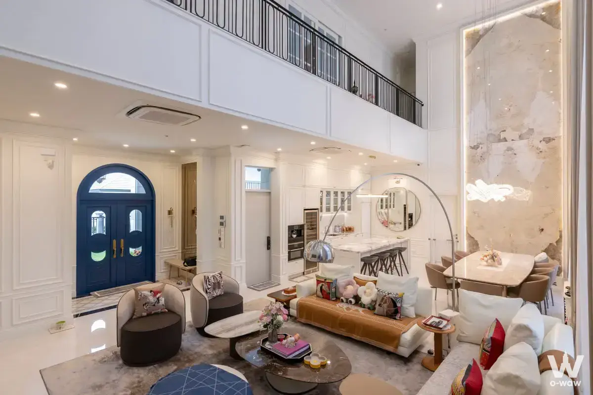 Double-height living room in a Narasiri Krungthep Kreetha house with navy arched doors and backlit stone feature wall
